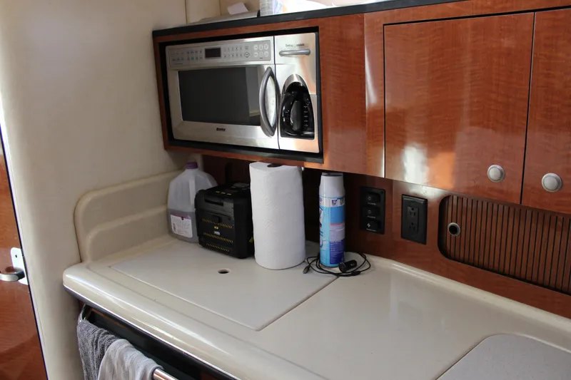 Slide: The Image of 2005 Sea Ray Sundancer 320 galley with microwave, wooden cabinets, and countertop essentials. - 33