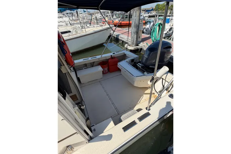 Slide: The Image of 1998 Rosborough RF-246 Sedan Cruiser at marina, featuring spacious deck and outboard motor. - 48