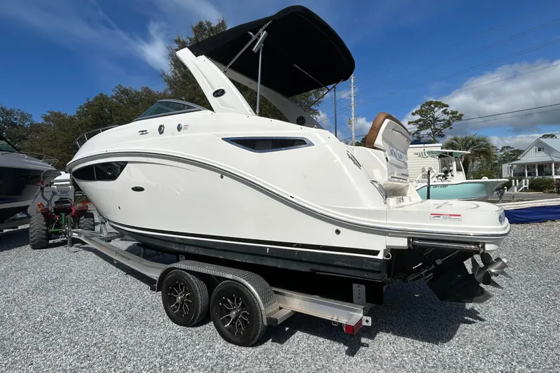 Slide: The Image of 2016 Sea Ray Sundancer 260 boat on trailer, white exterior, parked outdoors under blue sky. - 13