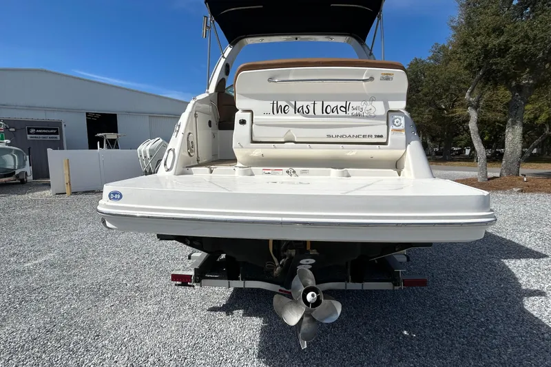 Slide: The Image of 2016 Sea Ray Sundancer 260 boat rear view on gravel lot, showcasing propeller and swim platform. - 14