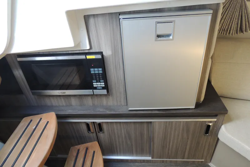 Slide: The Image of 2020 Sea Ray Sundancer 320 Outboard interior with microwave and fridge in cabin. - 12