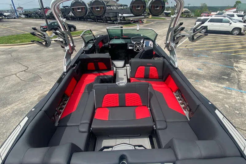 Slide: The Image of 2021 MasterCraft X26 boat interior with red and black seating, parked in a lot. - 11