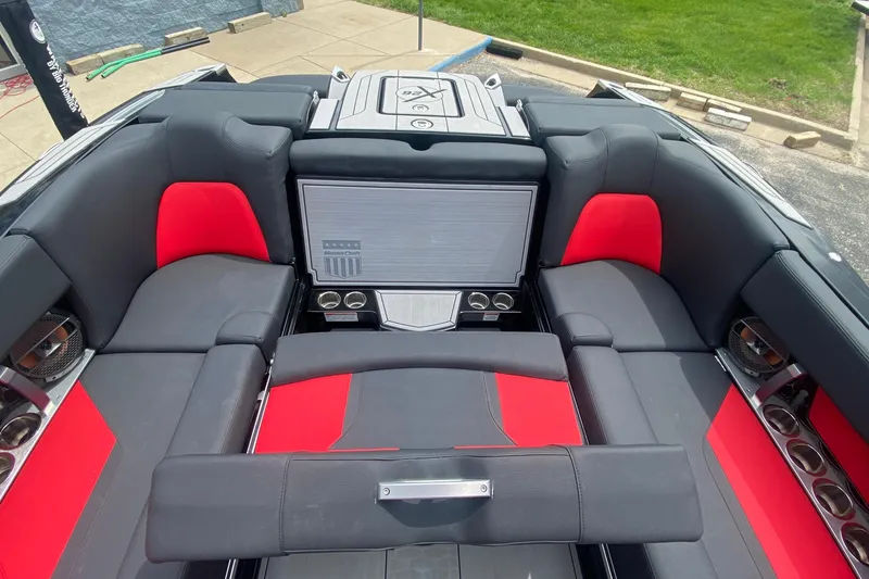Slide: The Image of 2021 MasterCraft X26 boat interior with red and black seating, cup holders, and premium audio system. - 16
