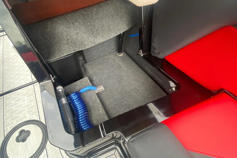 Slide: The Image of Interior storage compartment of 2021 MasterCraft X26 boat with red and black seating. - 20