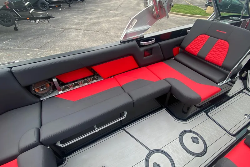 Slide: The Image of 2021 MasterCraft X26 boat interior with red and black seating, cup holders, and speaker. - 22