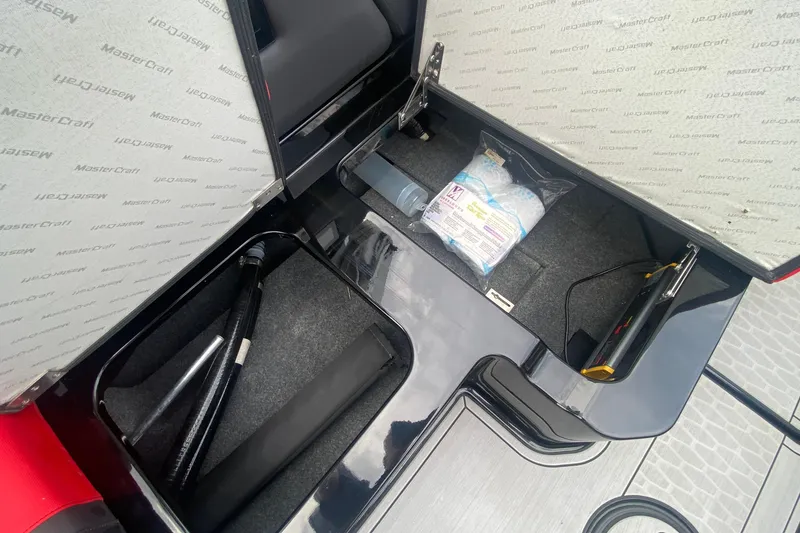 Slide: The Image of Open storage compartment in 2021 MasterCraft X26 boat, showing organized equipment and supplies. - 24