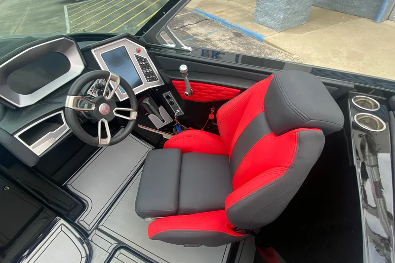 Slide: The Image of 2021 MasterCraft X26 boat interior with red and black captain's seat and modern dashboard. - 27