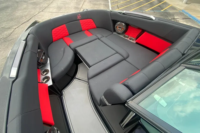 Slide: The Image of 2021 MasterCraft X26 boat interior with black and red seating, cup holders, and speakers. - 29