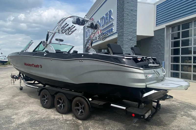 Slide: The Image of 2021 MasterCraft X26 boat on trailer outside dealership, showcasing sleek design and modern features. - 3