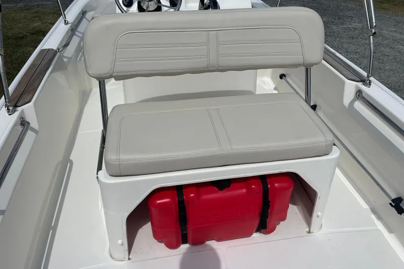 Slide: The Image of 2021 Boston Whaler 150 Montauk boat seat with red storage compartment underneath. - 11