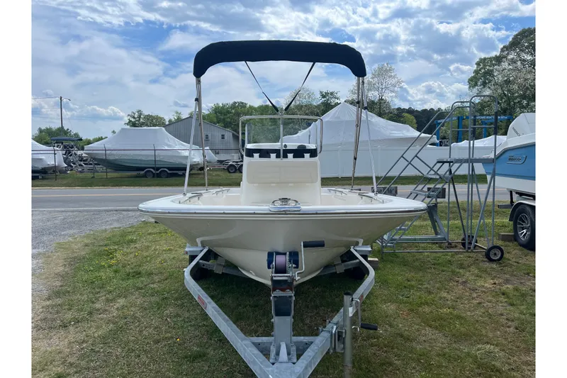 Slide: The Image of 2021 Boston Whaler 150 Montauk boat on trailer, parked outdoors under a cloudy sky. - 17