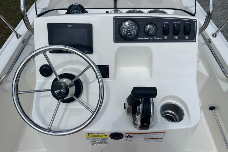 Slide: The Image of 2021 Boston Whaler 150 Montauk boat console with steering wheel and control panel. - 4