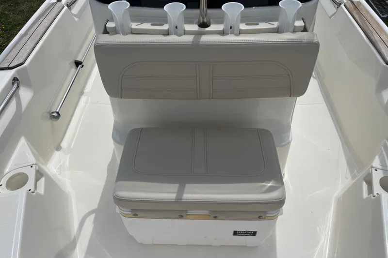 Slide: The Image of 2021 Boston Whaler 150 Montauk boat interior with cushioned seating and rod holders. - 9