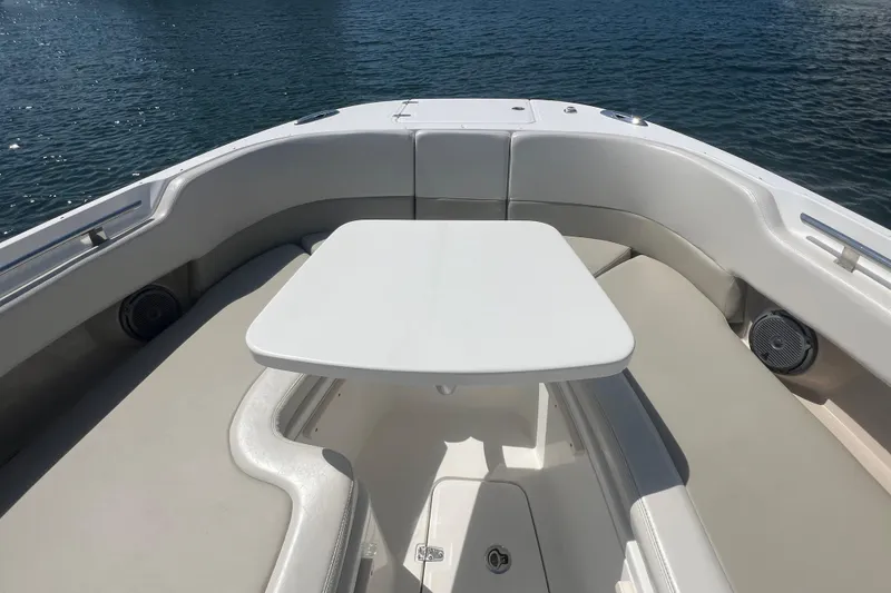 Slide: The Image of Bow seating area of a 2015 Boston Whaler 320 Vantage boat with table on calm water. - 16
