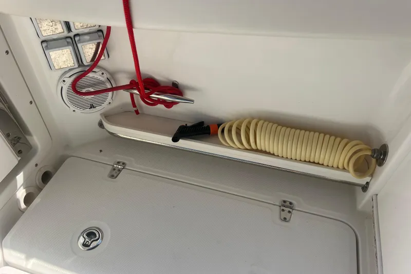 Slide: The Image of Storage compartment on a 2015 Boston Whaler 320 Vantage boat with hose and red rope. - 45