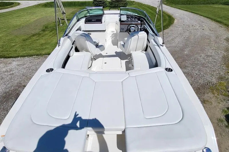 Slide: The Image of 2016 Sea Ray SLX 250 boat interior with white seating and dashboard, parked on grass. - 5