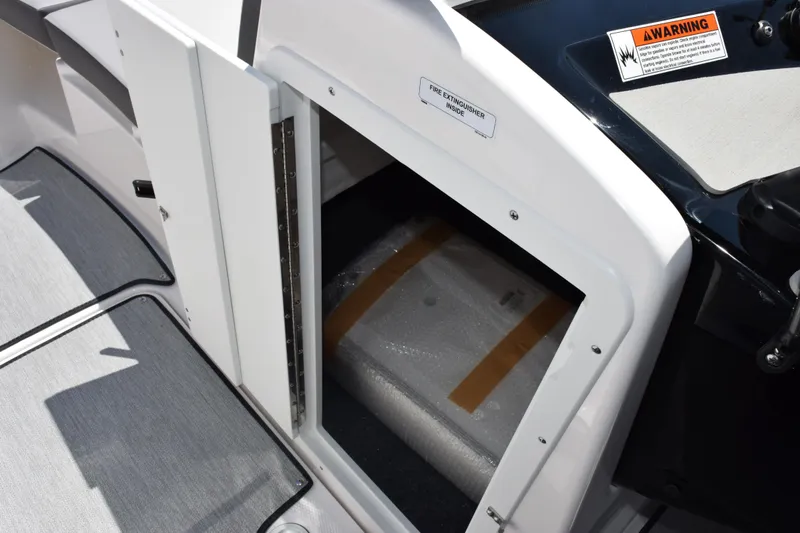 Slide: The Image of 2026 Yamaha Boats AR220 storage compartment with fire extinguisher inside, warning label visible. - 16