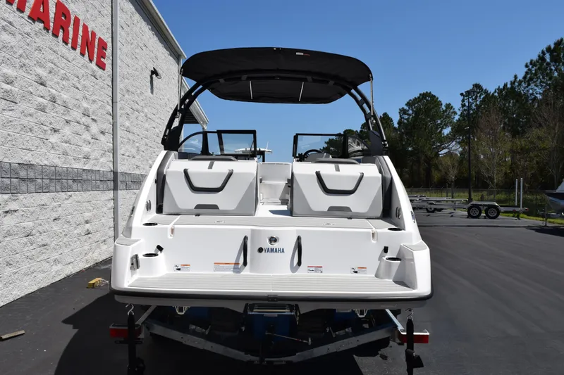 Slide: The Image of 2026 Yamaha Boats AR220, rear view, parked outdoors near a marine store. - 5