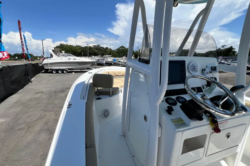 Slide: The Image of 2016 Sea Hunt Ultra 211 boat with steering console, docked under a clear blue sky. - 38