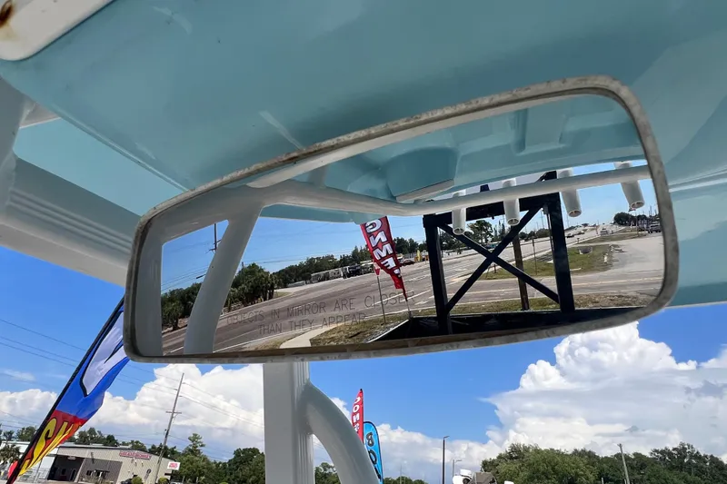 Slide: The Image of Rearview mirror on 2016 Sea Hunt Ultra 211 boat, reflecting outdoor scene with flags and sky. - 47