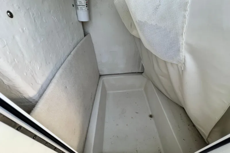 Slide: The Image of Interior compartment of a 2016 Sea Hunt Ultra 211 boat, featuring storage space and a fire extinguisher. - 53