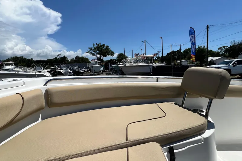Slide: The Image of 2016 Sea Hunt Ultra 211 boat interior with beige seating, parked at a marina under blue sky. - 59