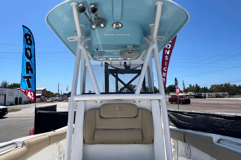 Slide: The Image of 2016 Sea Hunt Ultra 211 boat with T-top, displayed outdoors with sale banners. - 66