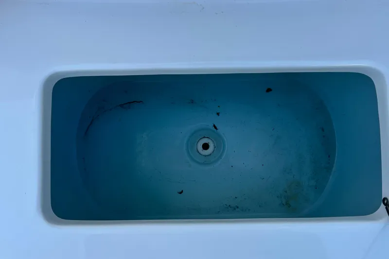 Slide: The Image of Livewell interior of 2016 Sea Hunt Ultra 211 boat, showing drain and slight debris. - 69