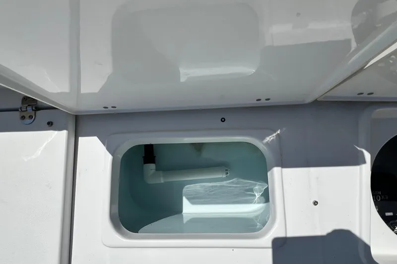 Slide: The Image of 2016 Sea Hunt Ultra 211 boat storage compartment with open lid and visible plumbing. - 72