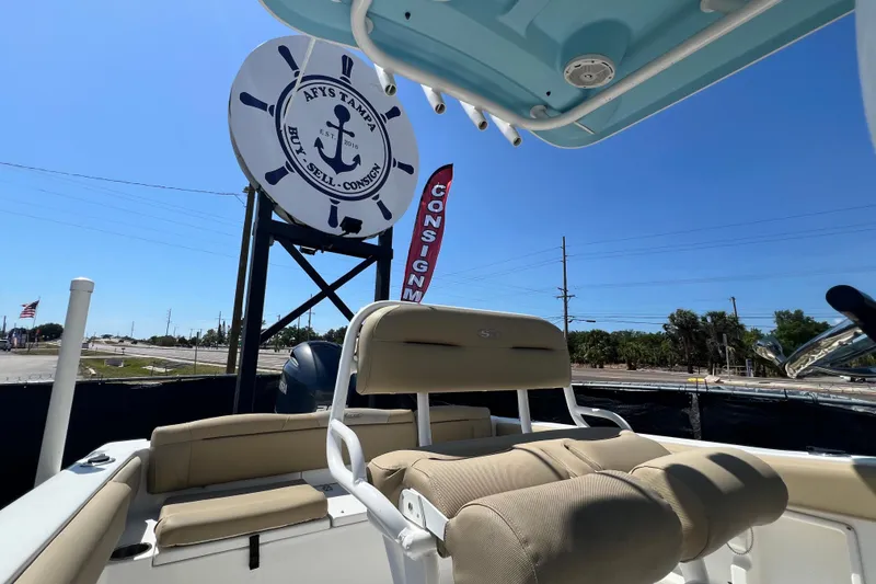 Slide: The Image of 2016 Sea Hunt Ultra 211 boat interior with consignment sign in background under clear blue sky. - 88