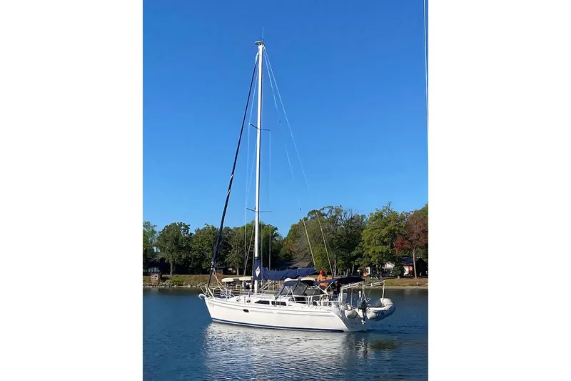 The Image of Catalina 310 sailboat from 2005 on calm water, surrounded by trees under a clear blue sky. - 1