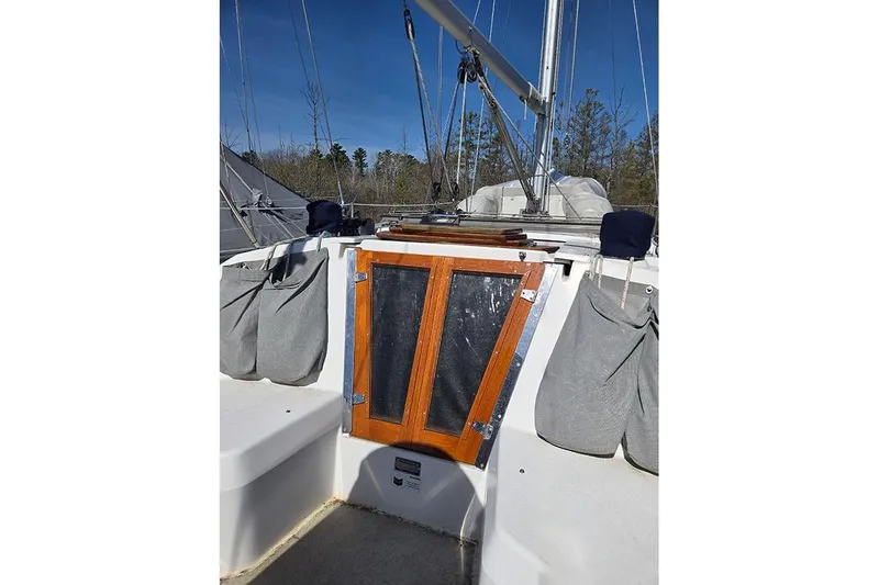 Slide: The Image of 2005 Catalina 310 sailboat cockpit with wooden hatch and gray storage bags. - 16