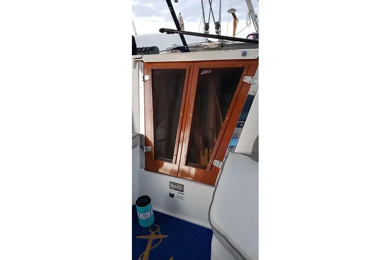 Slide: The Image of 2005 Catalina 310 sailboat cockpit with wooden hatch doors and blue mat. - 4