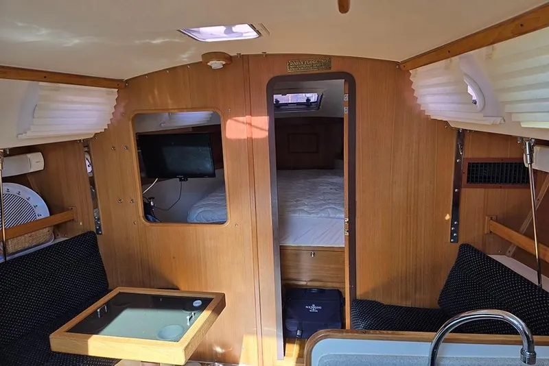Slide: The Image of Interior of a 2005 Catalina 310 sailboat, featuring cozy seating and a compact cabin. - 6