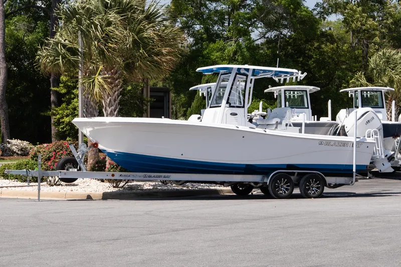 The Image of 2026 Blazer Bay Makaira 2600 boat on trailer, parked outdoors with trees in background. - 1