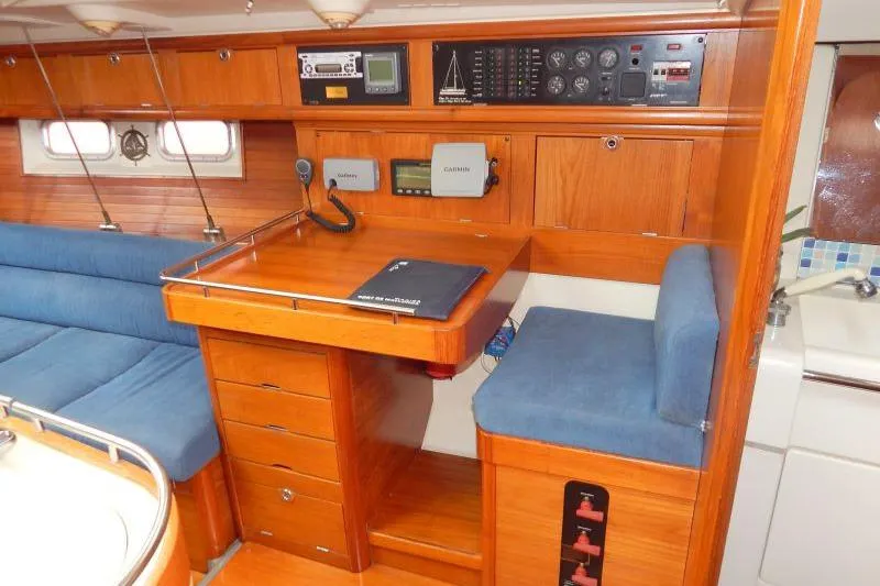 Slide: The Image of Navigation station inside a 1997 Etap 38i yacht with wooden cabinetry and blue seating. - 27