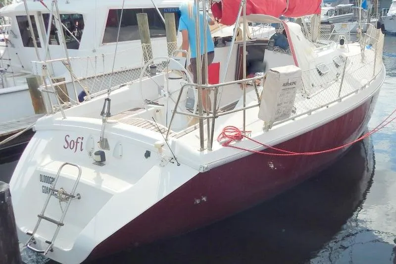 Slide: The Image of 1997 Etap 38i sailboat docked, featuring red hull and white deck, named "Sofi". - 4