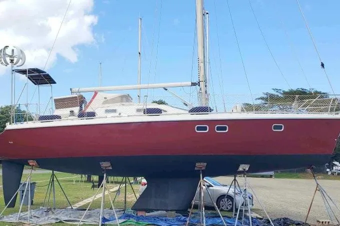 Slide: The Image of Etap 38i sailboat from 1997 on stands, with a red hull and white deck. - 51