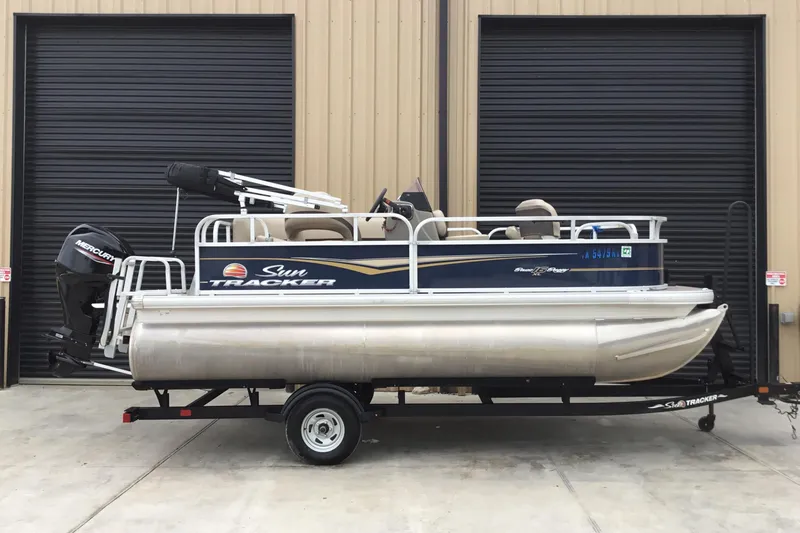 The Image of 2022 Sun Tracker Bass Buggy 16 XL pontoon boat on trailer, parked outside. - 1