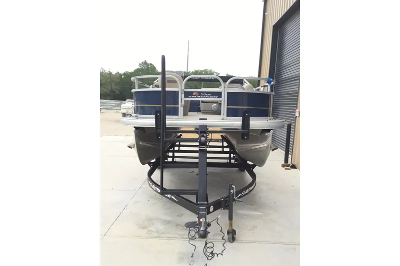 Slide: The Image of 2022 Sun Tracker Bass Buggy 16 XL pontoon boat on trailer, parked outside a garage. - 4