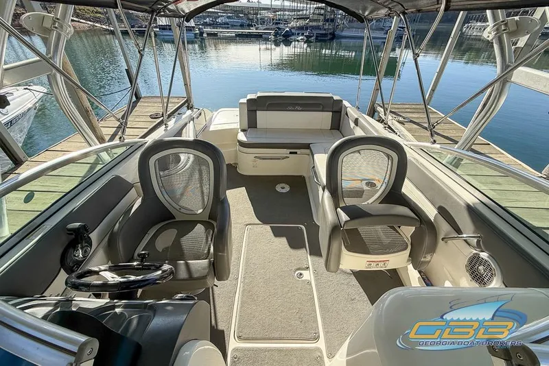 Slide: The Image of 2011 Sea Ray 260 Sundeck interior with seating and steering wheel, docked at marina. - 2
