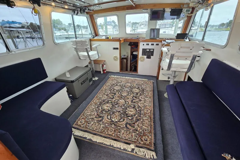 Slide: The Image of Interior of a 1995 MDI Down East boat with navy seating and ornate rug. - 4
