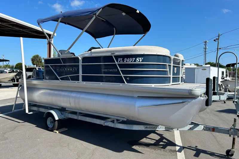 The Image of 2021 Godfrey Sweetwater 1880 CX pontoon boat on trailer, parked outdoors. - 1