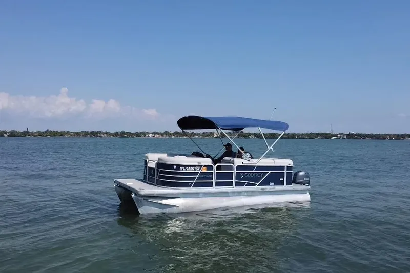 Slide: The Image of 2021 Godfrey Sweetwater 1880 CX pontoon boat cruising on a calm lake under clear skies. - 17