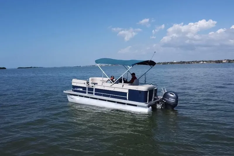 Slide: The Image of 2021 Godfrey Sweetwater 1880 CX pontoon boat cruising on a calm lake under a clear sky. - 18