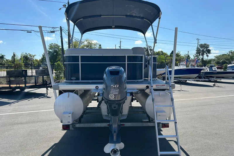 Slide: The Image of 2021 Godfrey Sweetwater 1880 CX pontoon boat with canopy and outboard motor in a parking lot. - 3