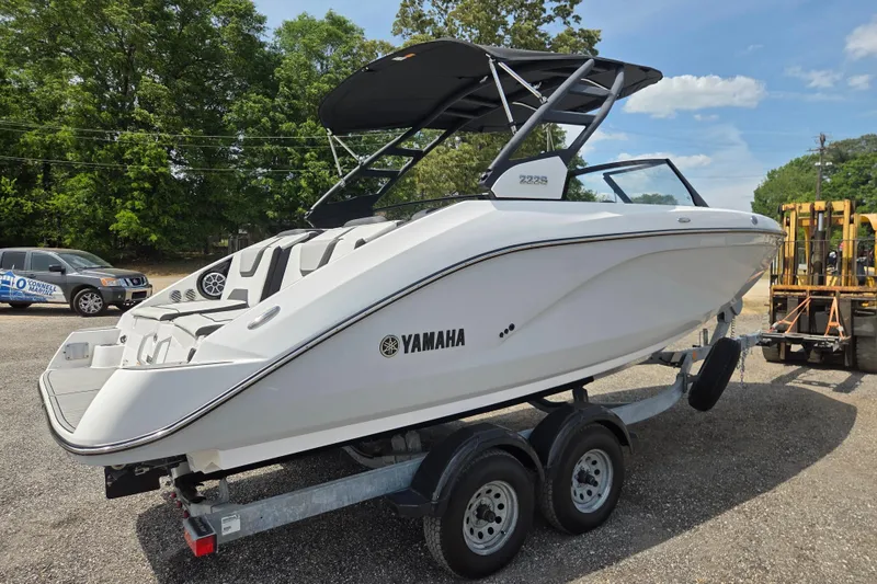 Slide: The Image of 2023 Yamaha Boats 222S on trailer, sleek white design, parked outdoors. - 4