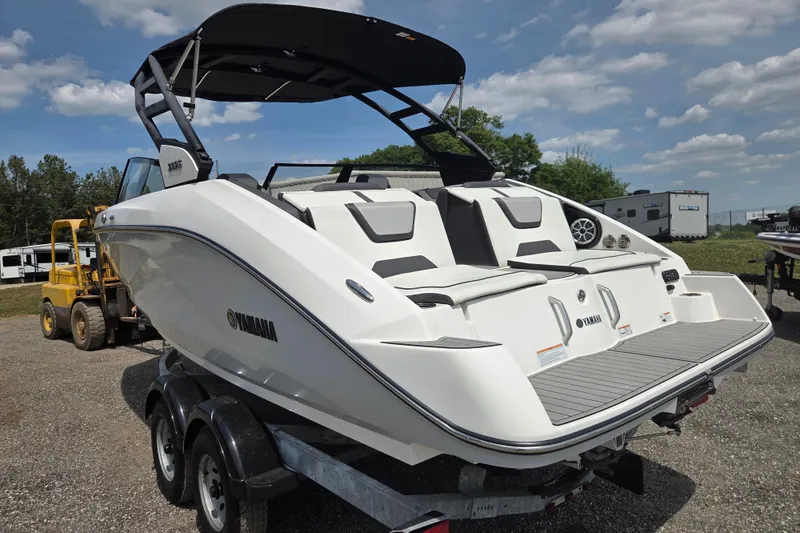 Slide: The Image of 2023 Yamaha Boats 222S, sleek white design, on trailer, under blue sky. - 7