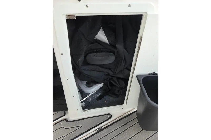 Slide: The Image of Storage compartment on 2023 Yamaha Boats 222S, featuring interior items and adjacent container. - 9