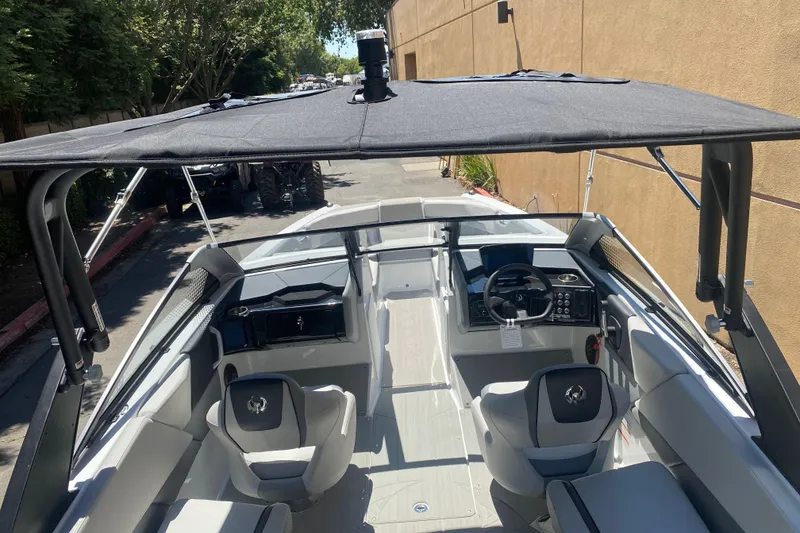 Slide: The Image of 2025 Scarab 235 SE boat interior with modern seating and steering, under a shaded canopy. - 22